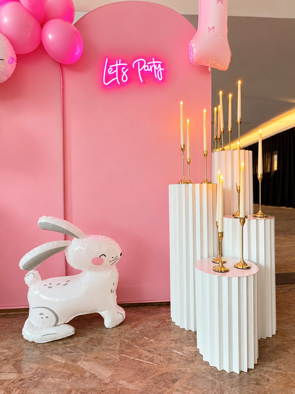 Geburtstagsdeko in Rosa mit Neon-Schriftzug, weißen Säulen und goldenen Kerzenständern